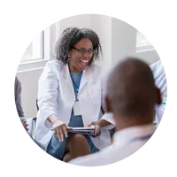 A woman in white lab coat holding a tablet.