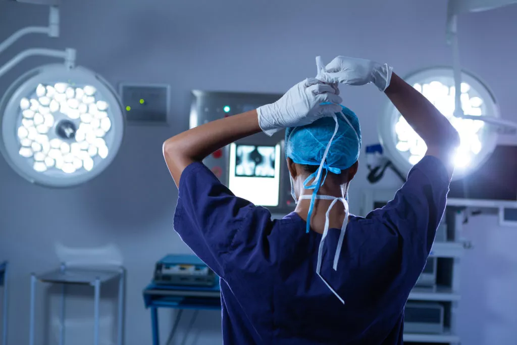 A surgeon in the operating room holding up his hands.