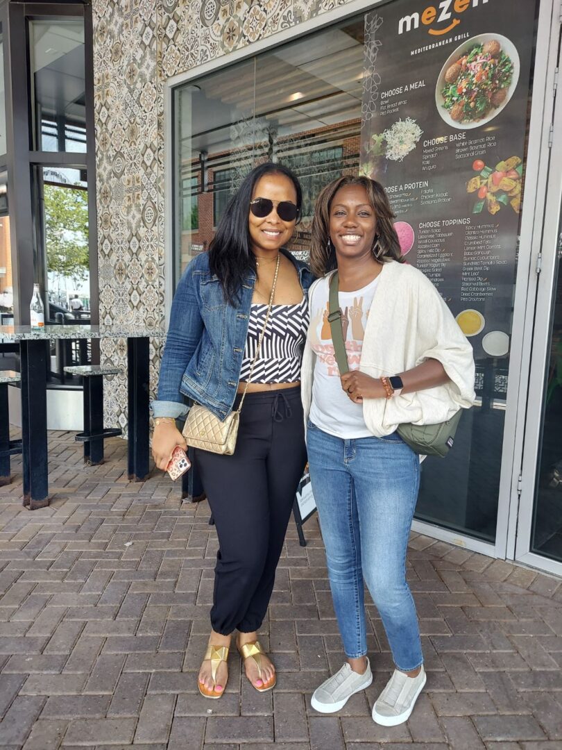 Two women standing next to each other on a sidewalk.