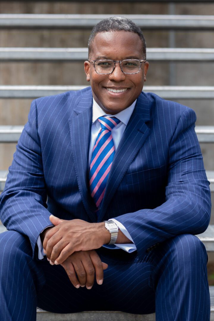 A man in a blue suit sitting on steps.