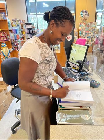 A woman is writing on paper at the counter.