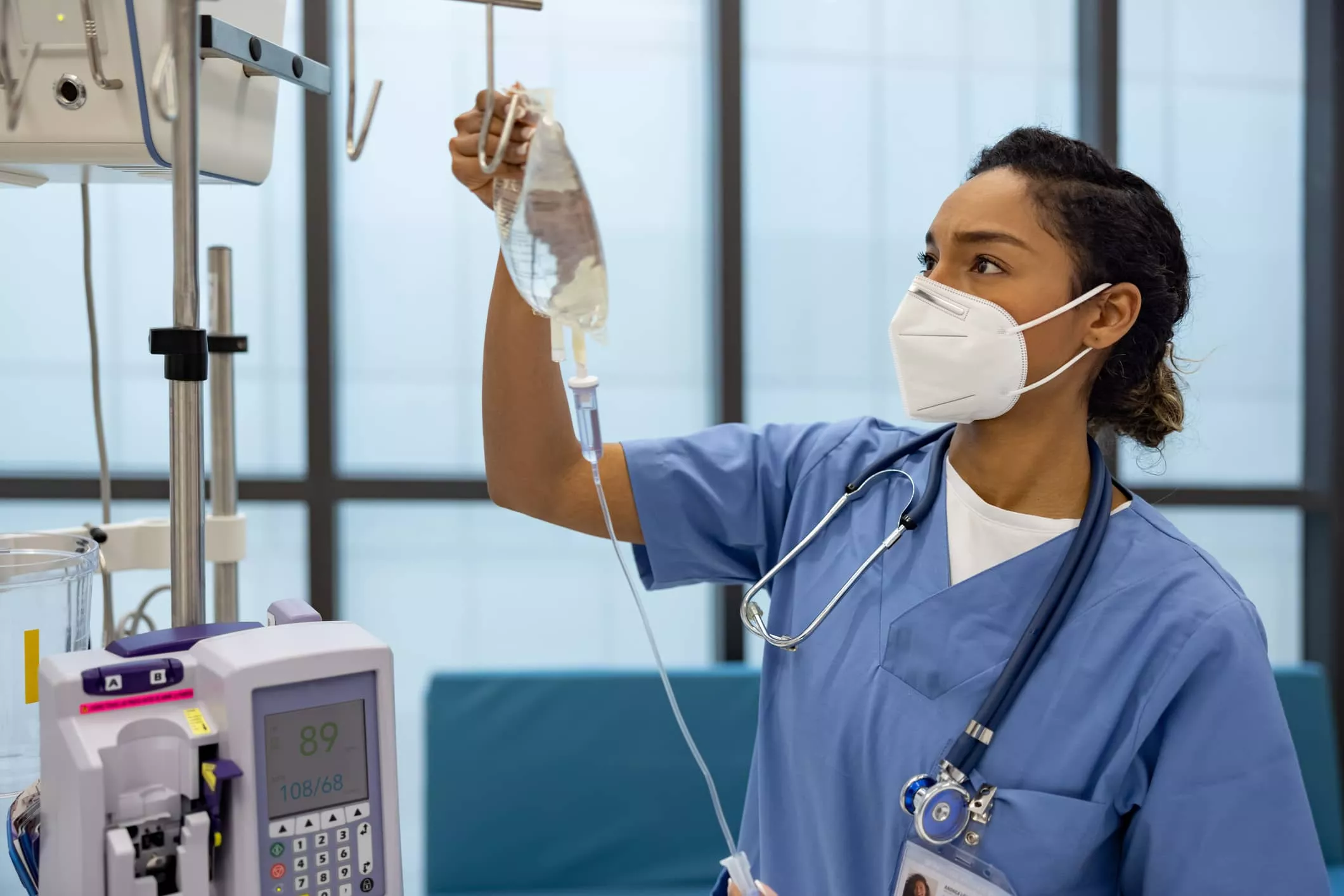A nurse in scrubs holding up an iv tube.
