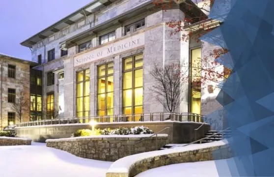 A building with snow on the ground and trees in front of it.