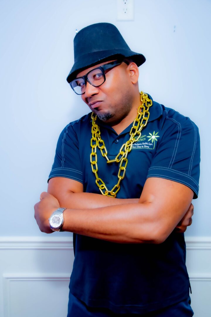 A man with his arms crossed wearing glasses and a hat.