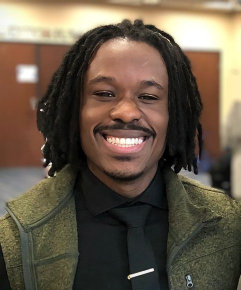 A man with dreadlocks is smiling for the camera.