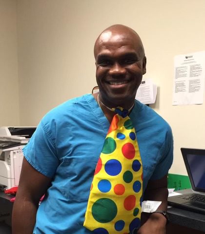 A man wearing a colorful tie in front of a laptop.