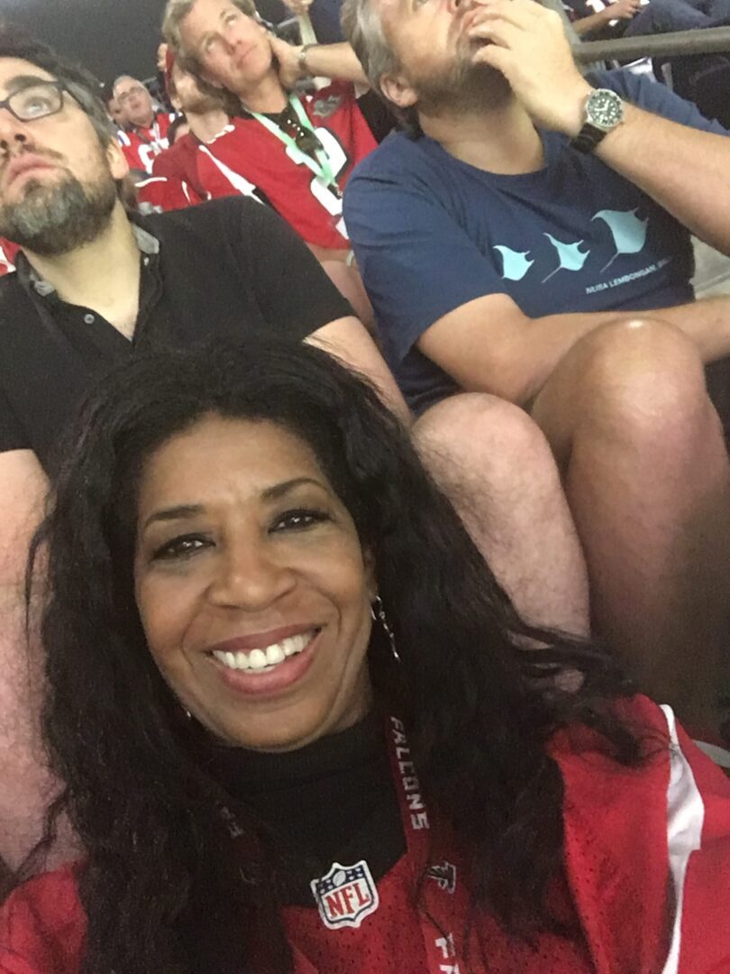 A woman smiles for the camera while sitting in front of other people.