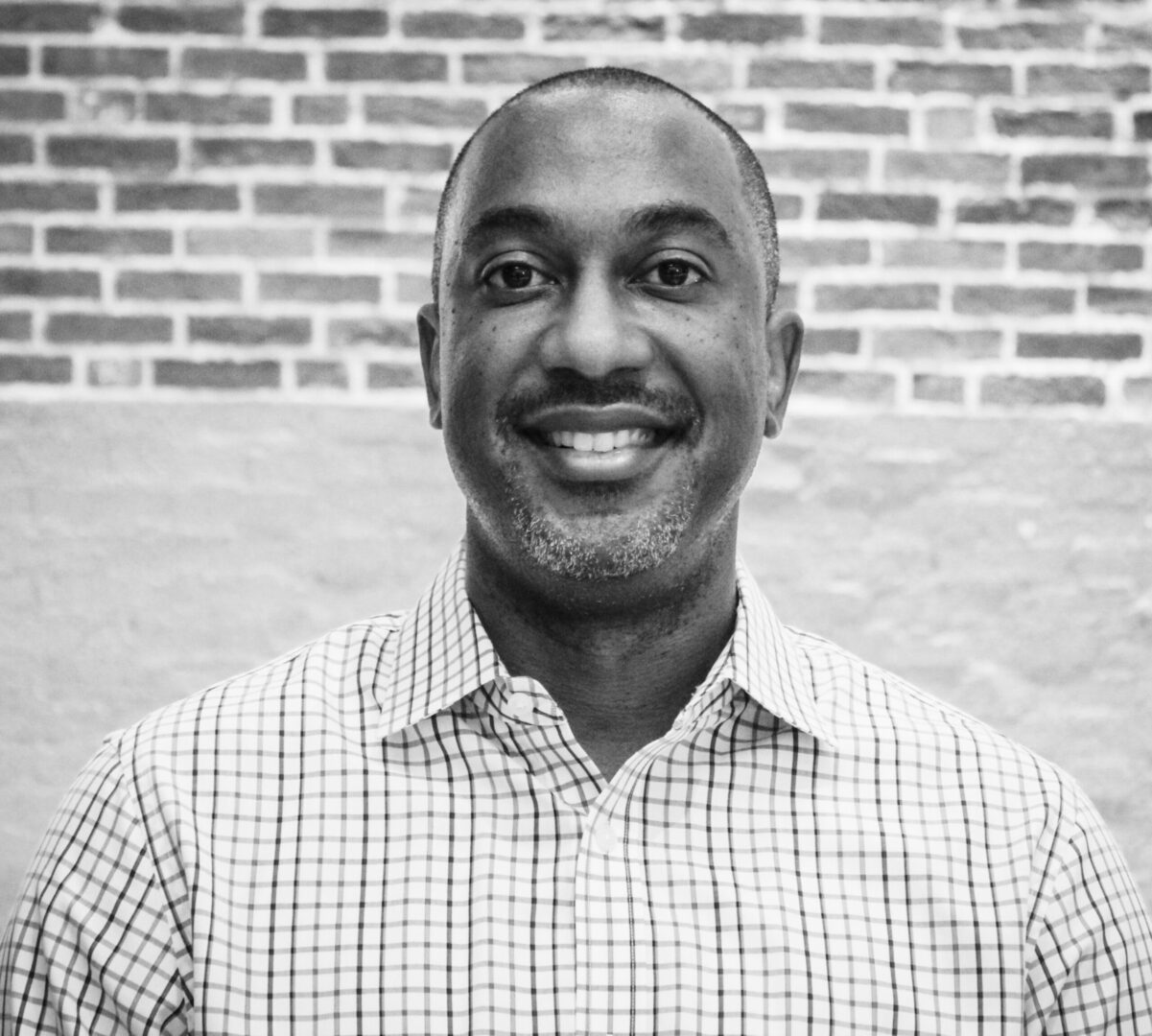 A black and white photo of a man smiling.