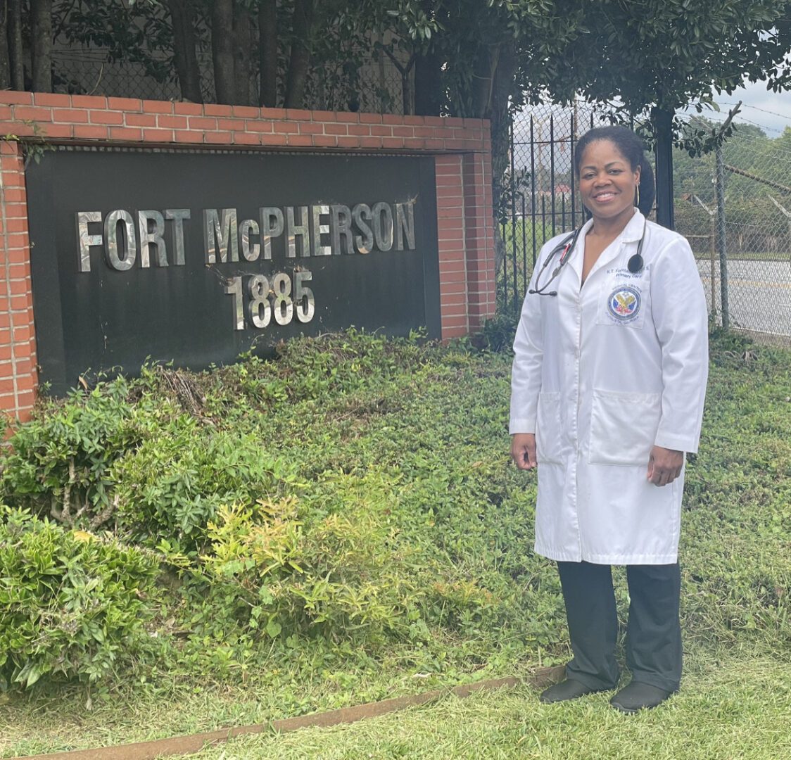 A woman in white lab coat standing outside of a building.