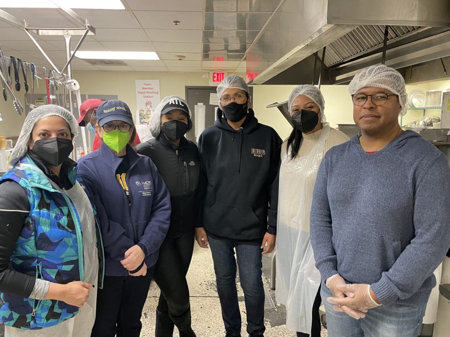 A group of people standing in a room wearing masks.