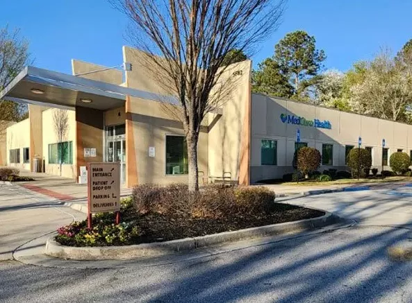A building with trees and bushes in front of it.