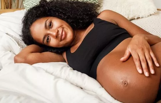 A woman laying in bed with her stomach exposed.