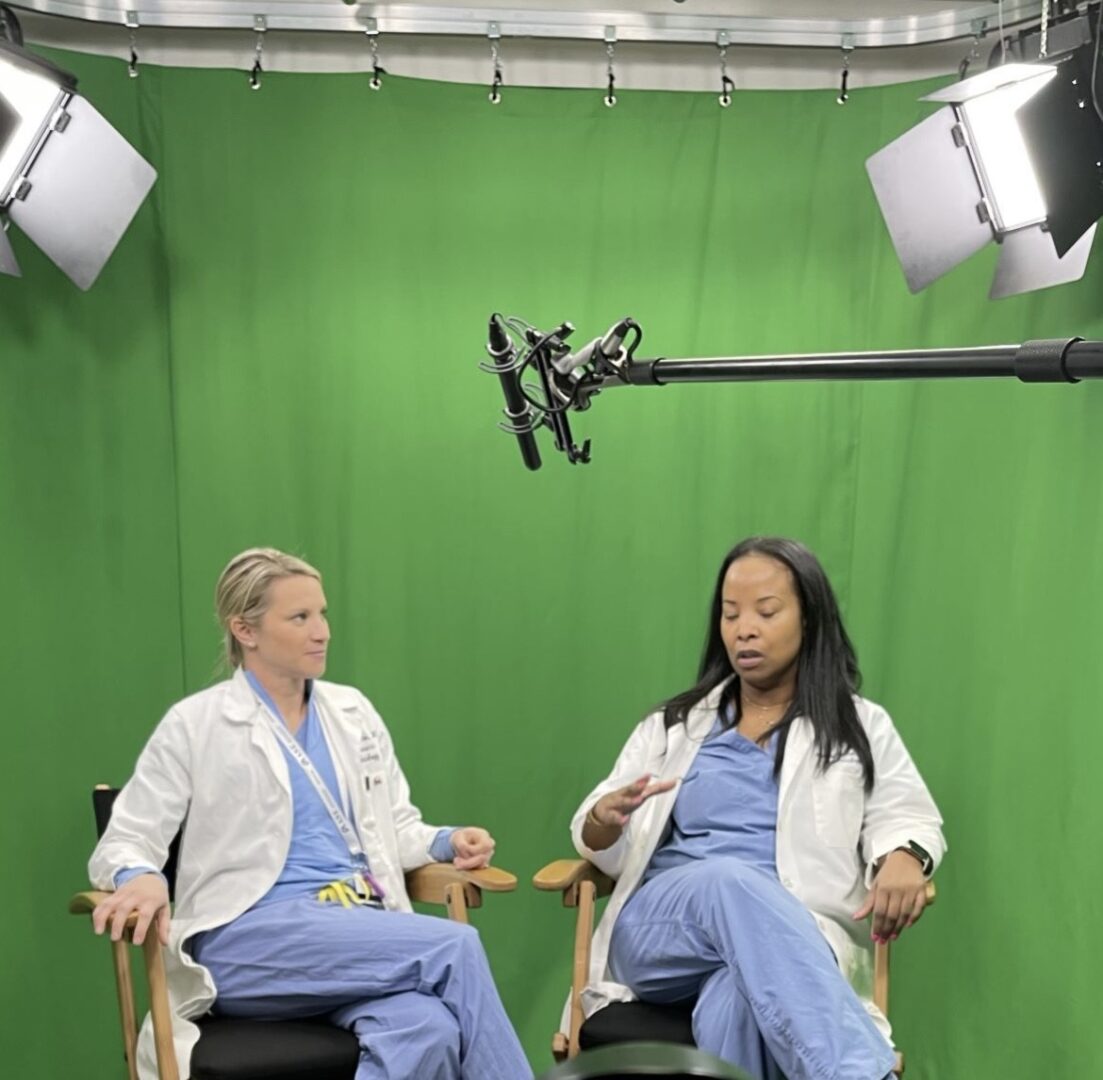 Two doctors sitting in a chair with green screen behind them.