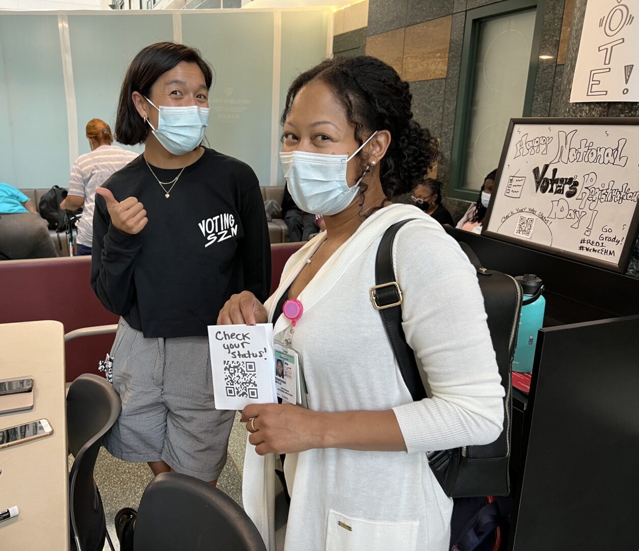 Two women wearing masks stand in a room.