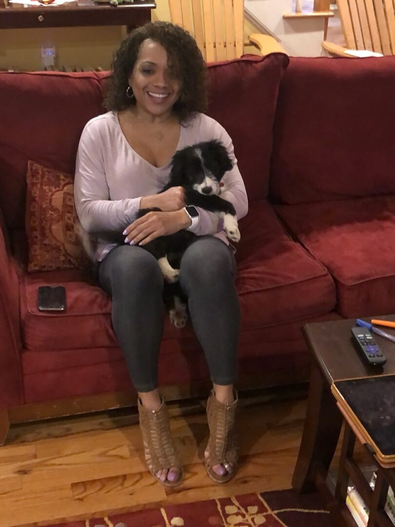 A woman sitting on the couch holding her dog.