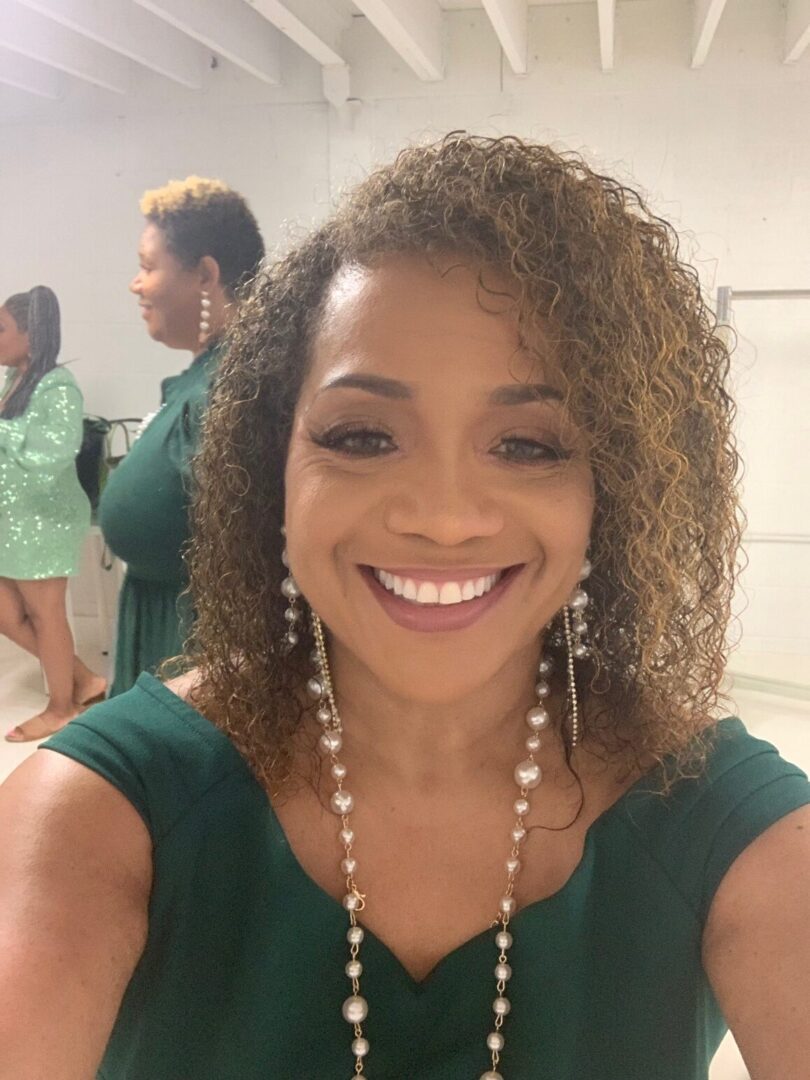 A woman with curly hair and green dress.