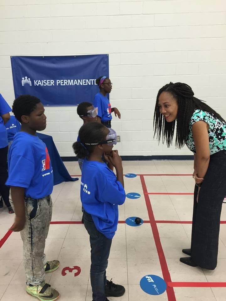 A group of kids standing around talking to a woman.