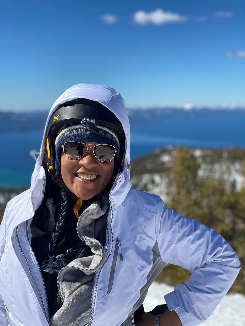 A woman in white jacket standing on top of hill.