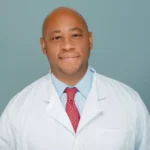 A man in white lab coat and red tie.