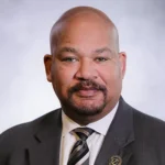 A man in suit and tie with a beard.