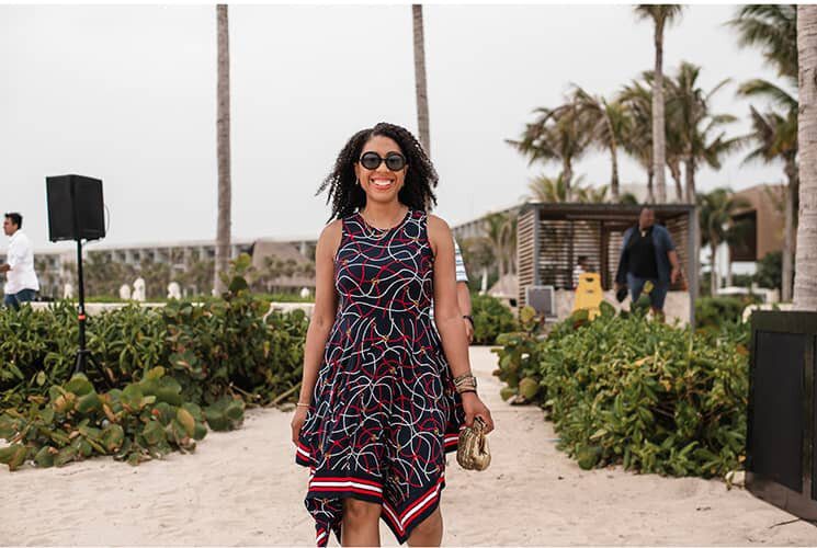 A woman in a black and red dress standing on the beach.