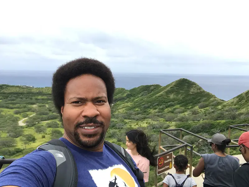 A man taking a selfie while standing on top of a hill.
