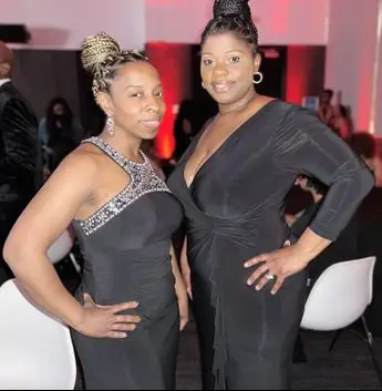 Two women in black dresses posing for a picture.