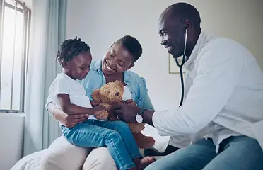 A doctor is holding a teddy bear and a child.