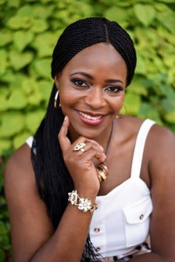 A woman with black hair and white dress smiling.