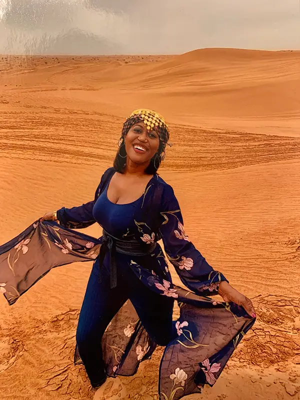 A woman in blue and black outfit holding onto a scarf.