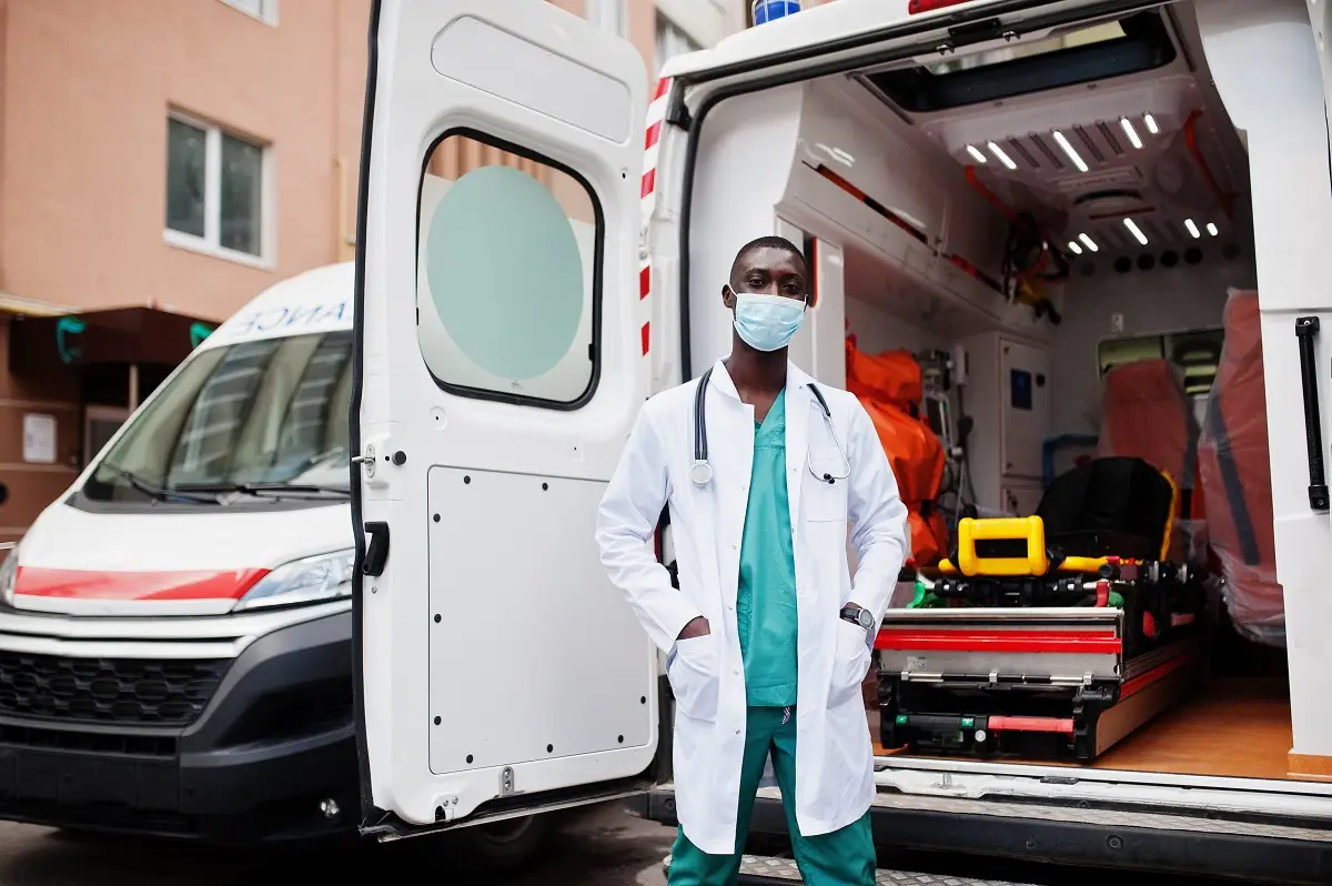 A doctor standing in front of an ambulance.