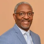 A man in a suit and tie smiling for the camera.