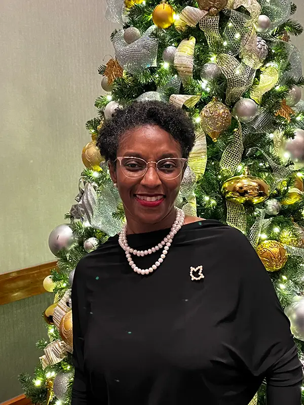 A woman standing in front of a christmas tree.