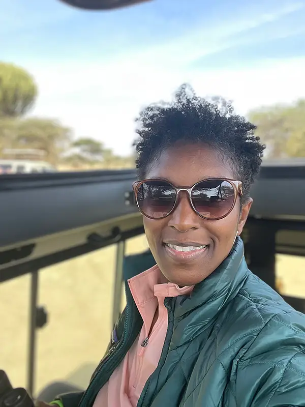 A woman with sunglasses on and smiling for the camera.