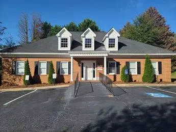 A large brick building with three windows and a fence.