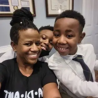 A woman and two boys are smiling for the camera.
