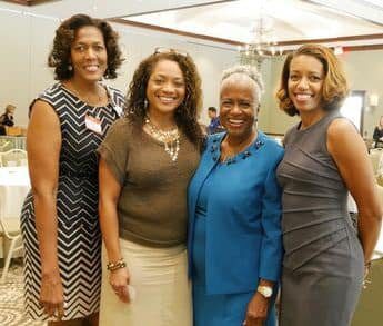 Four women standing next to each other in a room.