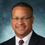 A man in suit and tie smiling for the camera.