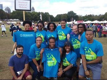 A group of people wearing blue shirts and smiling.