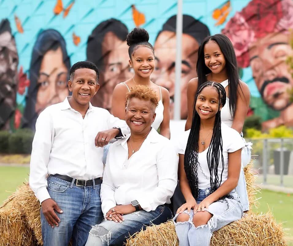 A family posing for a picture in front of a mural.