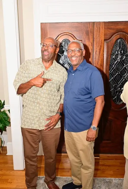 Two men standing next to each other in front of a door.