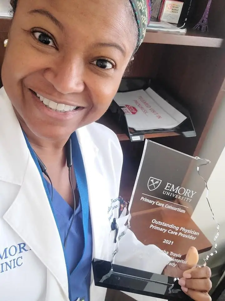 A woman holding up an award in front of a window.