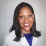A woman in white lab coat smiling for the camera.