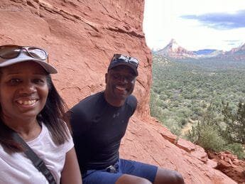 A man and woman sitting on the side of a cliff.