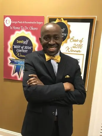 A man in a suit and bow tie standing next to a wall.