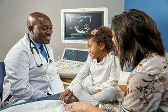 A doctor and two women sitting in front of a monitor.