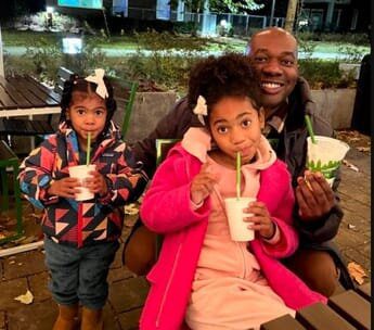 A man and two girls are drinking from cups.