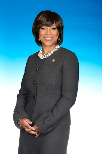 A woman in black jacket and white necklace.