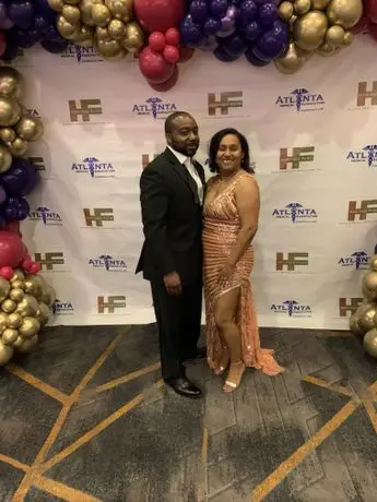 A man and woman posing for a picture in front of balloons.