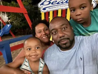A family posing for a picture in front of a beach.